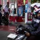 Papan informasi harga bahan bakar minyak di SPBU Pertamina dengan latar belakang suasana jalan raya.