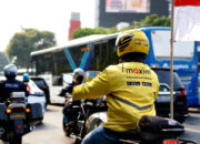Pengemudi ojek daring Maxim sedang menunggu penumpang di pinggir jalan Jakarta.