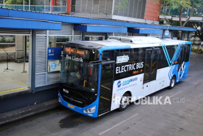 Bus Transjakarta beroperasi di jalanan Jakarta dengan latar belakang suasana kota pada malam hari.