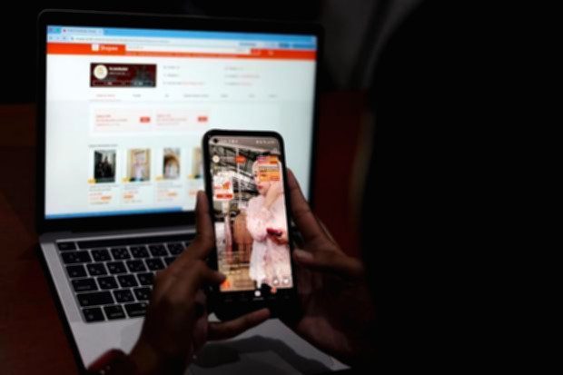 Ilustrasi transaksi belanja online di layar ponsel pintar dengan latar belakang perkantoran Jakarta