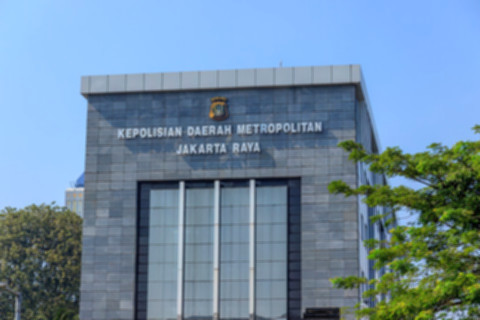 Logo Polda Metro Jaya dengan latar belakang gedung kantor polisi di Jakarta.